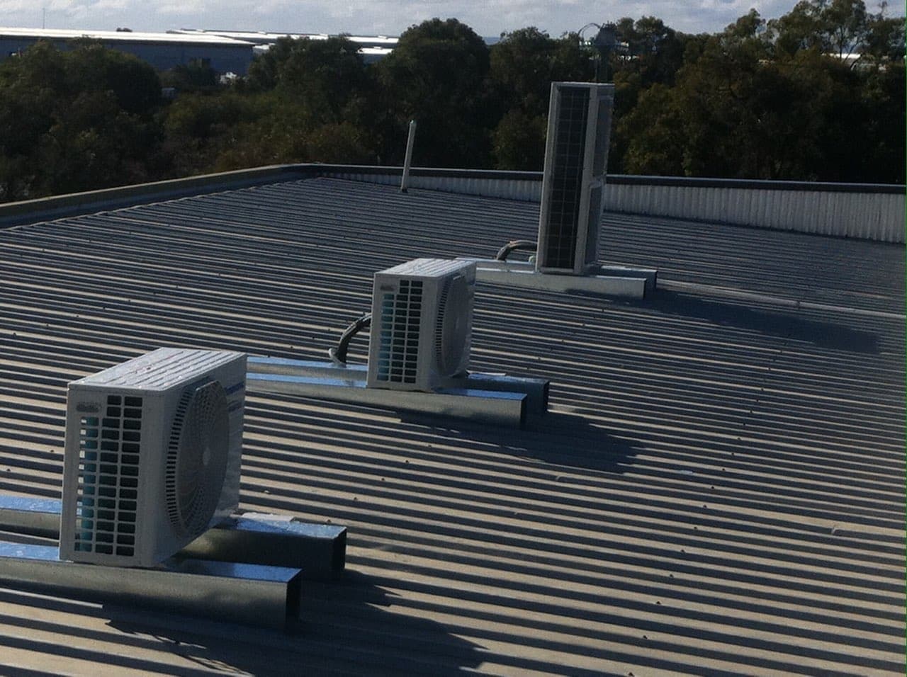 Two split system condenser units mounted on a flat commercial metal roof