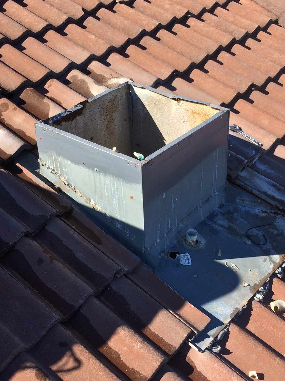 Galvanised drop box and lead flashing fitted into a tiled roof, ready for the unit to be seated